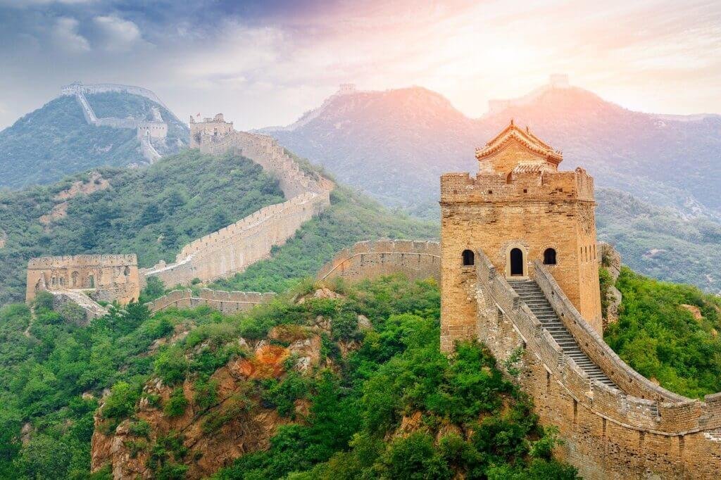 A scenic view of the Great Wall of China, an iconic historical landmark, winding through mountains and forests.