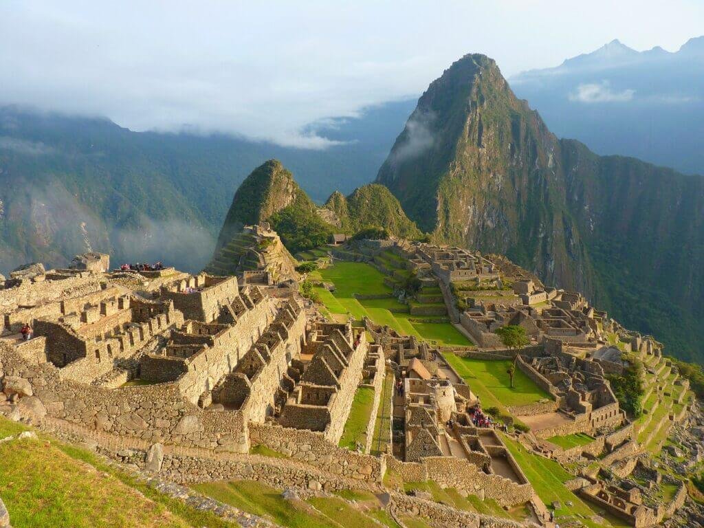 A breathtaking view of Machu Picchu, a top historical site in Peru, surrounded by lush green mountains under a clear sky.