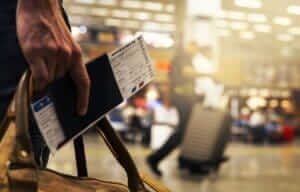 A close-up of a person holding a boarding pass and passport, symbolizing flexible travel plans to save on cheap flights.