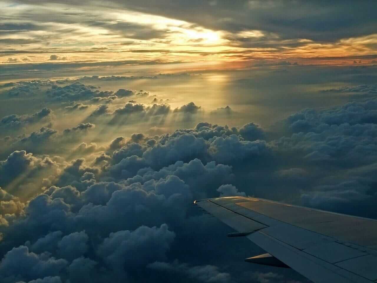 A serene aerial view of a flight during sunset above the clouds, perfect for travel inspiration.