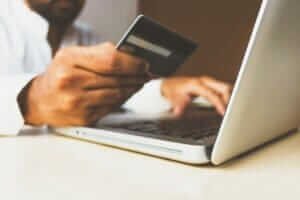 Person holding a credit card while booking a flight online, representing using points and miles for cheap flights.